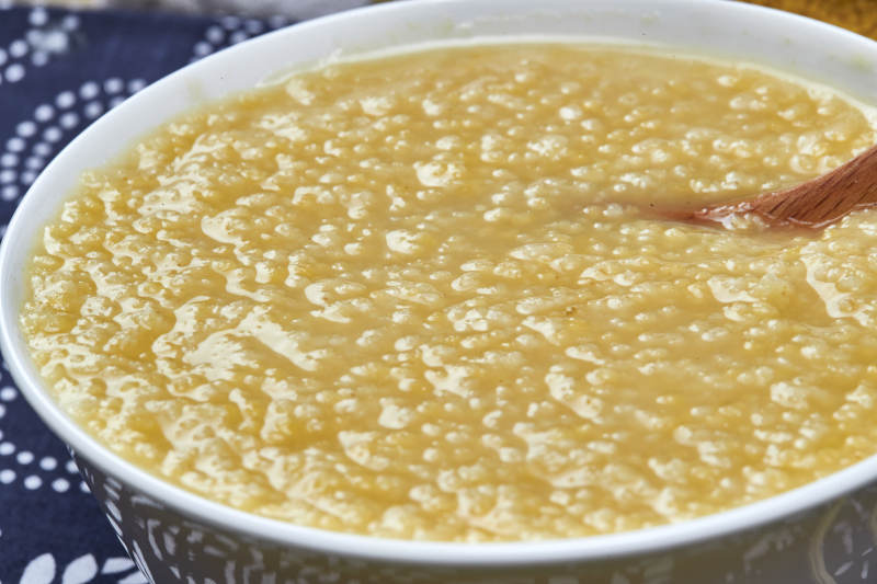 手持木勺㧟起的美味香浓小米粥