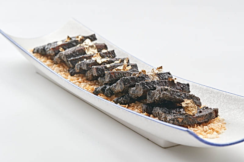 白色瓷盘装的墨鱼汁香煎猪五花肉