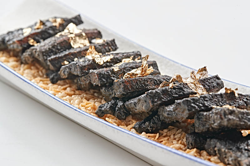 白色瓷盘装的墨鱼汁香煎猪五花肉