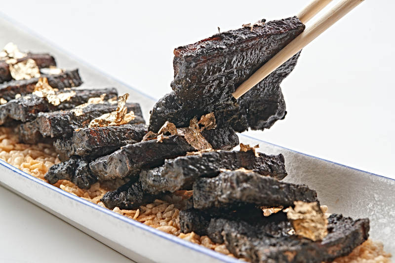 白色瓷盘装的墨鱼汁香煎猪五花肉