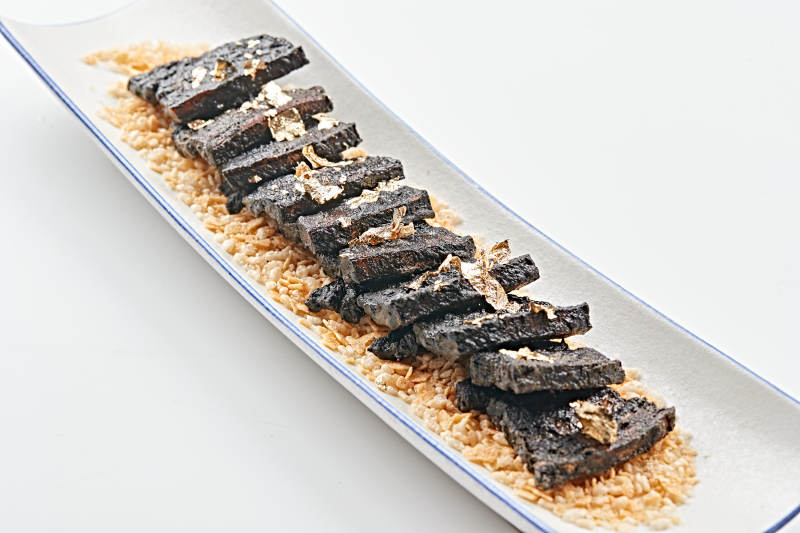 白色瓷盘装的墨鱼汁香煎猪五花肉