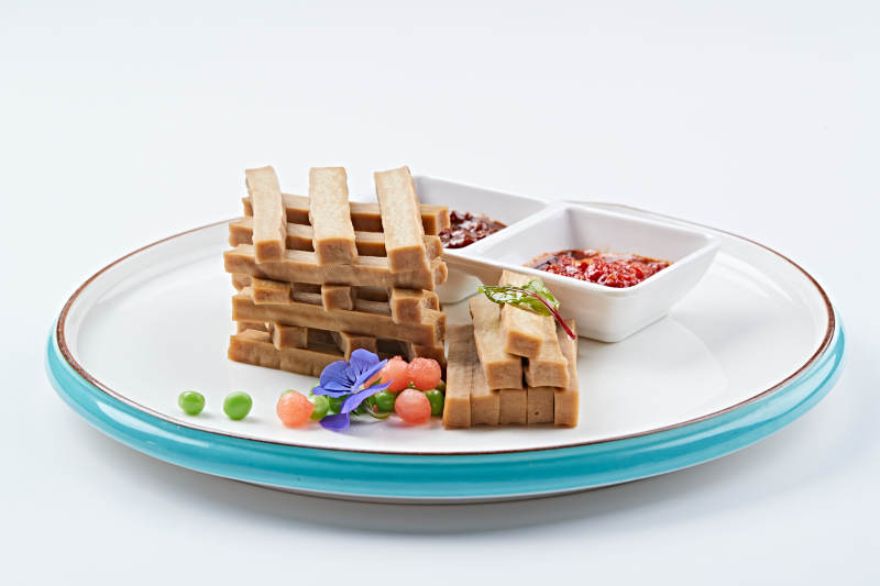 白色瓷盘装的蘸酱烟熏豆干