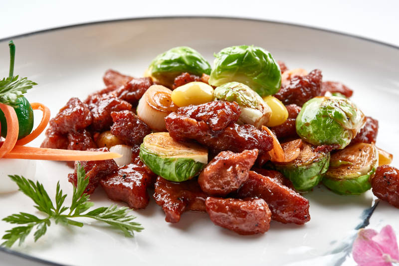 白色瓷盘装的酱爆银杏小甘蓝黑胡椒牛仔粒