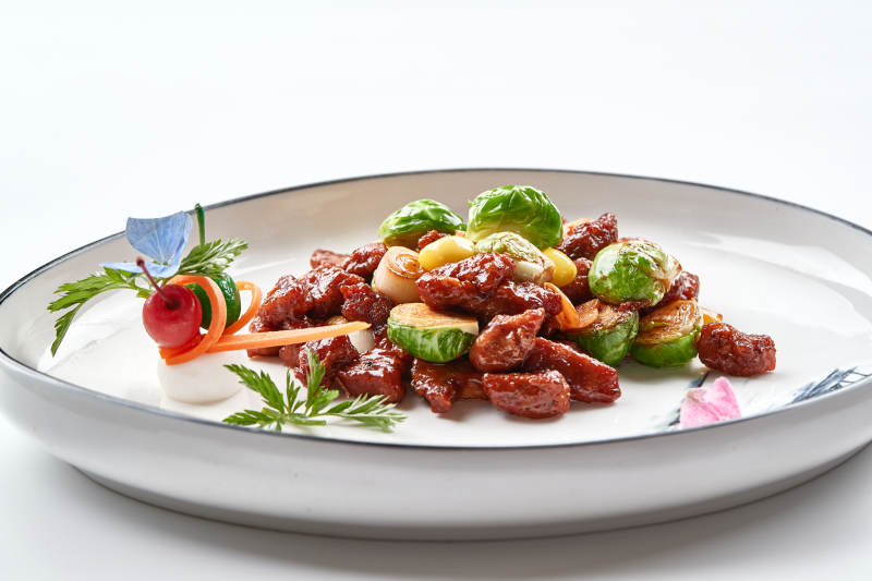 白色瓷盘装的酱爆银杏小甘蓝黑胡椒牛仔粒