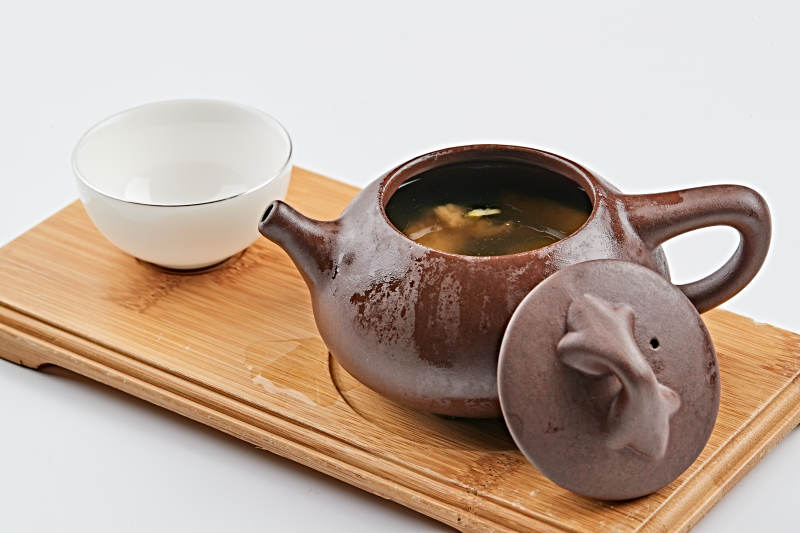 白色背景上摆放的紫砂当归土鸡汤