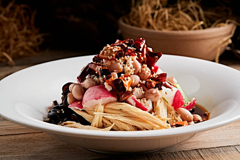 白色瓷盘装的捞汁果仁木耳黄瓜拌腐竹