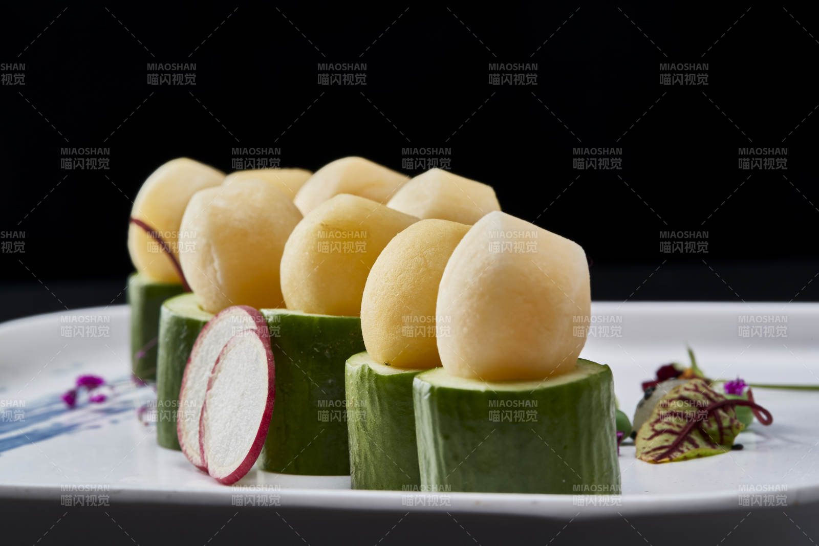 黑色背景上的创意美食手打马铃薯球配乳瓜段