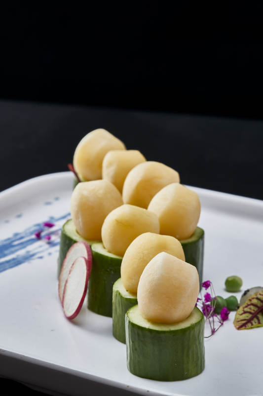 黑色背景上的創(chuàng)意美食手打馬鈴薯球配乳瓜段