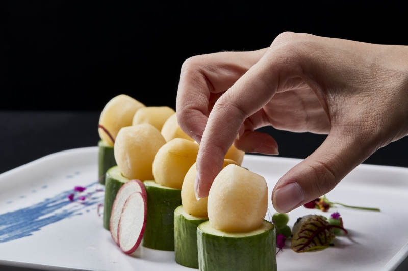 黑色背景上的創(chuàng)意美食手打馬鈴薯球配乳瓜段