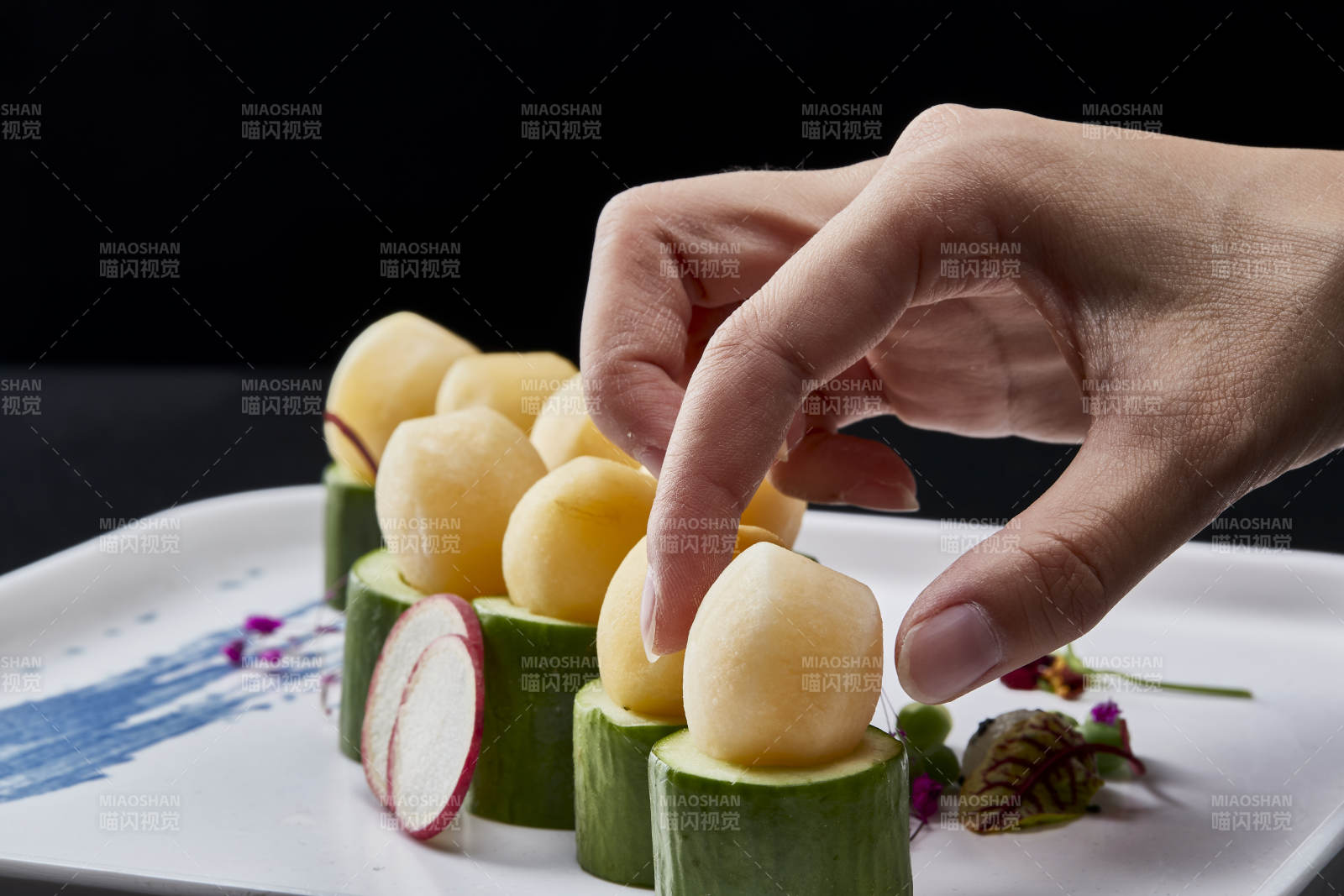 黑色背景上的創(chuàng)意美食手打馬鈴薯球配乳瓜段