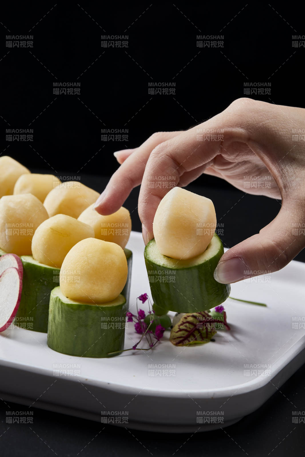 黑色背景上的創(chuàng)意美食手打馬鈴薯球配乳瓜段