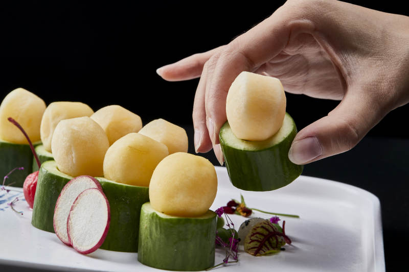 黑色背景上的創(chuàng)意美食手打馬鈴薯球配乳瓜段