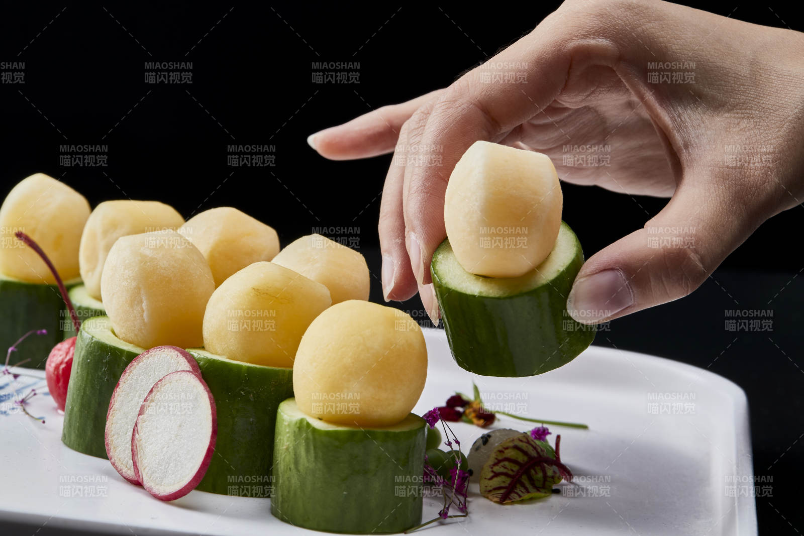 黑色背景上的創(chuàng)意美食手打馬鈴薯球配乳瓜段