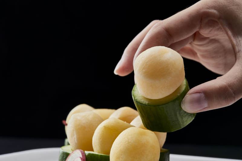 黑色背景上的創(chuàng)意美食手打馬鈴薯球配乳瓜段