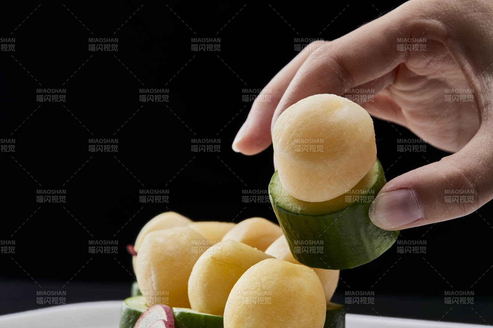 黑色背景上的創意美食手打馬鈴薯球配乳瓜段