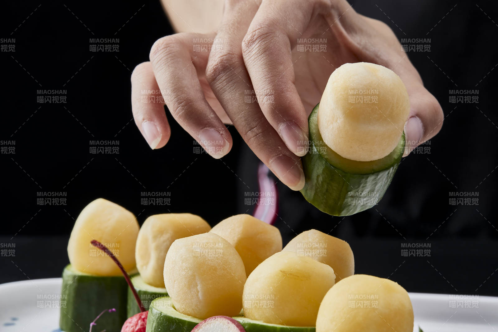 黑色背景上的創(chuàng)意美食手打馬鈴薯球配乳瓜段