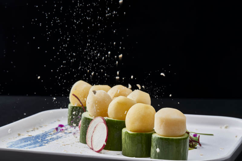 黑色背景上的創(chuàng)意美食手打馬鈴薯球配乳瓜段