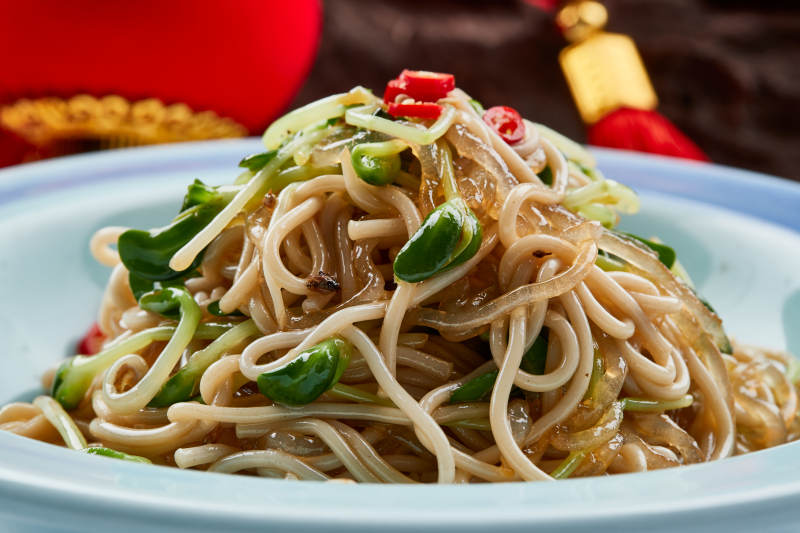 青色瓷餐具裝的黑豆苗涼拌莜面饸饹