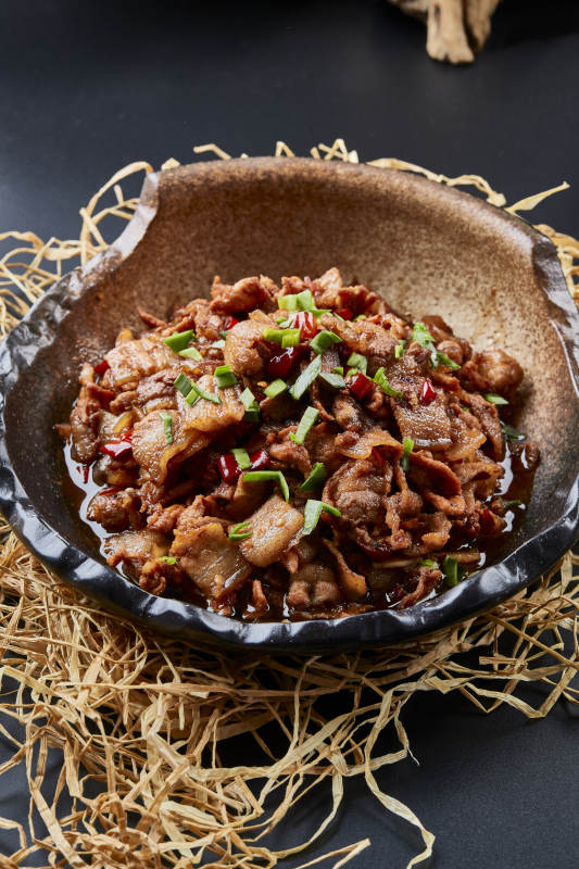 黑色背景上的陶碗装的肥肉炒瘦肉