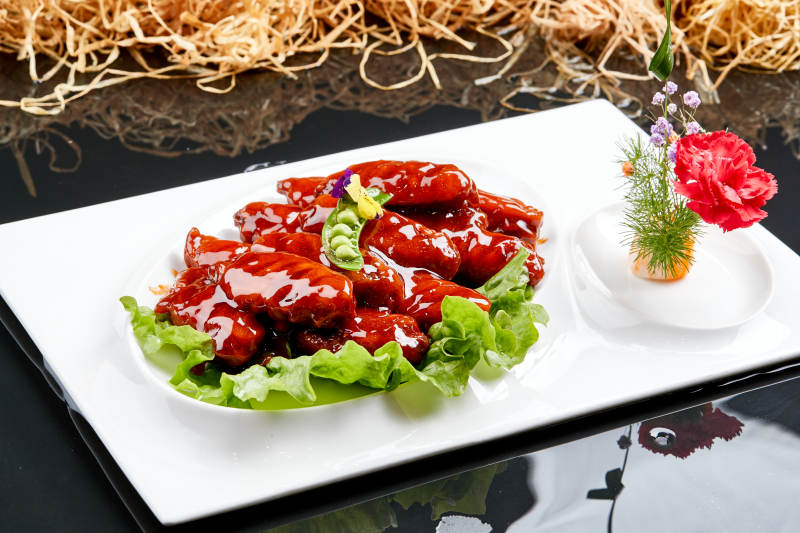 白色瓷盘装的蜜豆酱鸡翅中