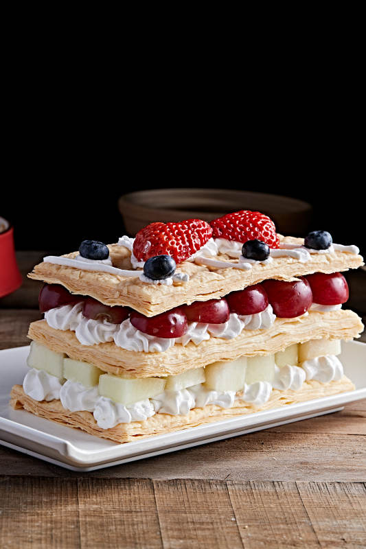 白色瓷盘装的水果戚风奶油拿破仑蛋糕