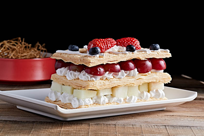 白色瓷盘装的水果戚风奶油拿破仑蛋糕