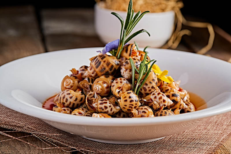 白色瓷盘装的红油腌渍小花螺