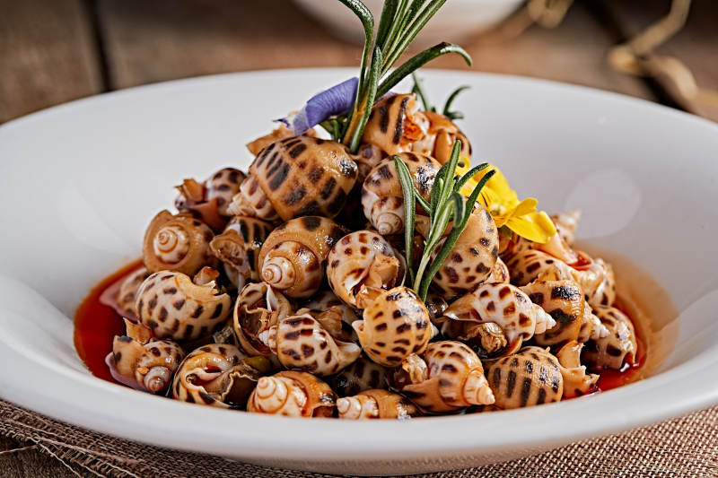 白色瓷盘装的红油腌渍小花螺