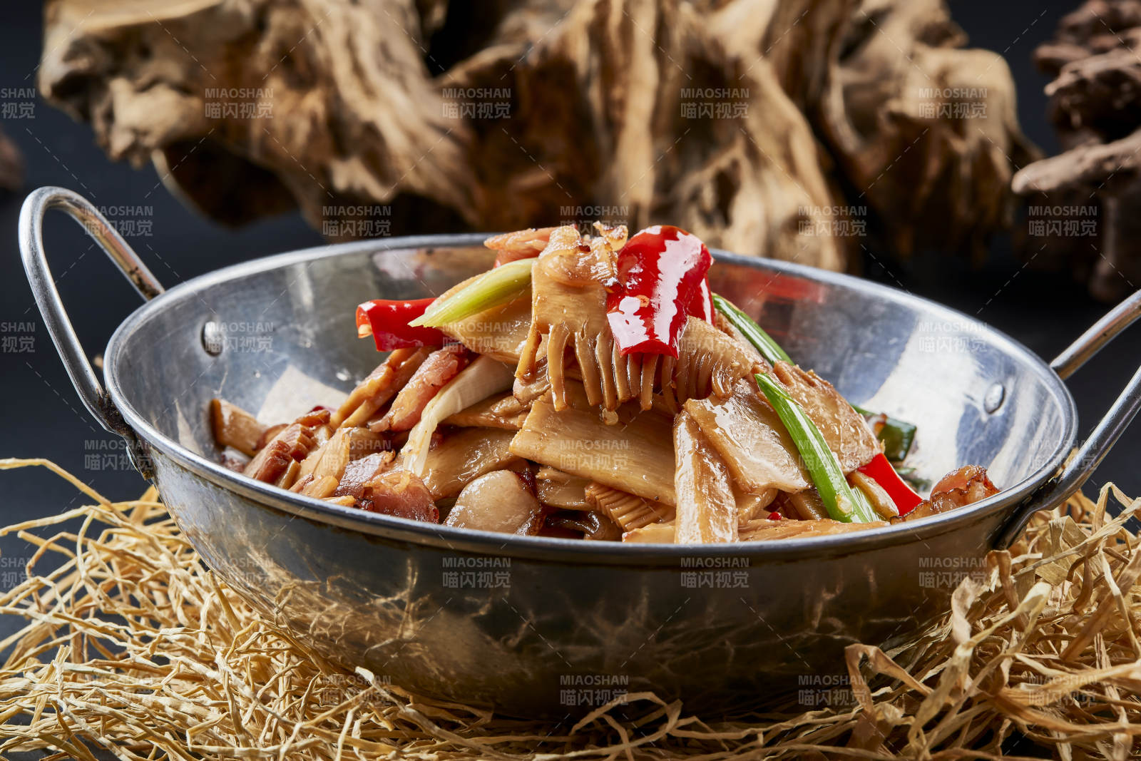 黑色背景上的鍋仔香辣臘肉煲鮮筍