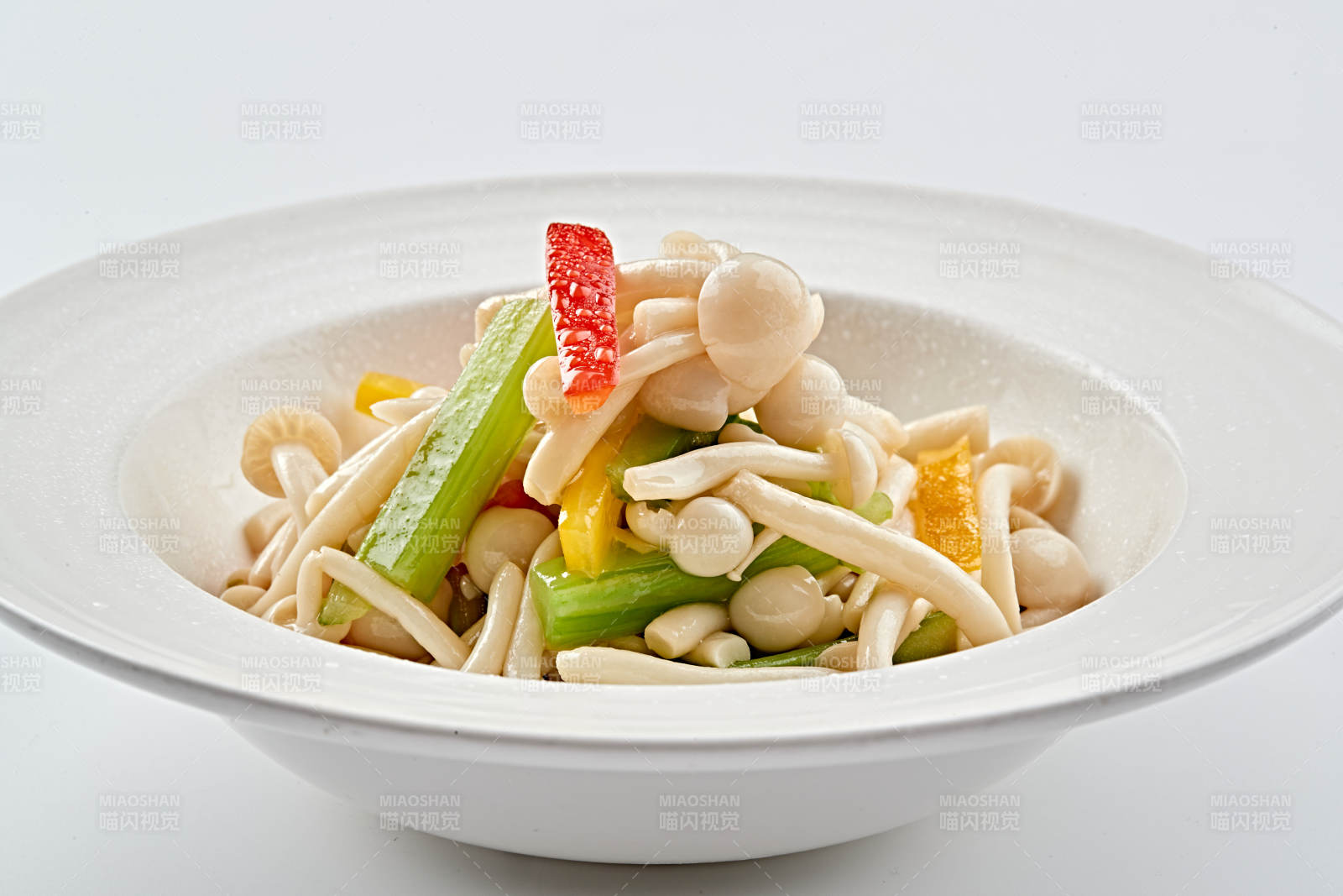 白色瓷盘装的西芹彩椒小炒白玉菇