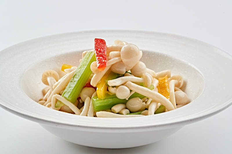 白色瓷盘装的西芹彩椒小炒白玉菇