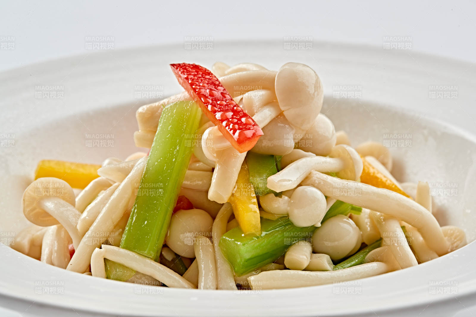 白色瓷盘装的西芹彩椒小炒白玉菇