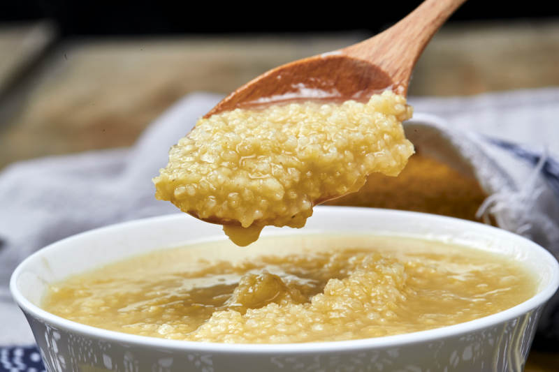 手持木勺㧟起的美味香浓小米粥