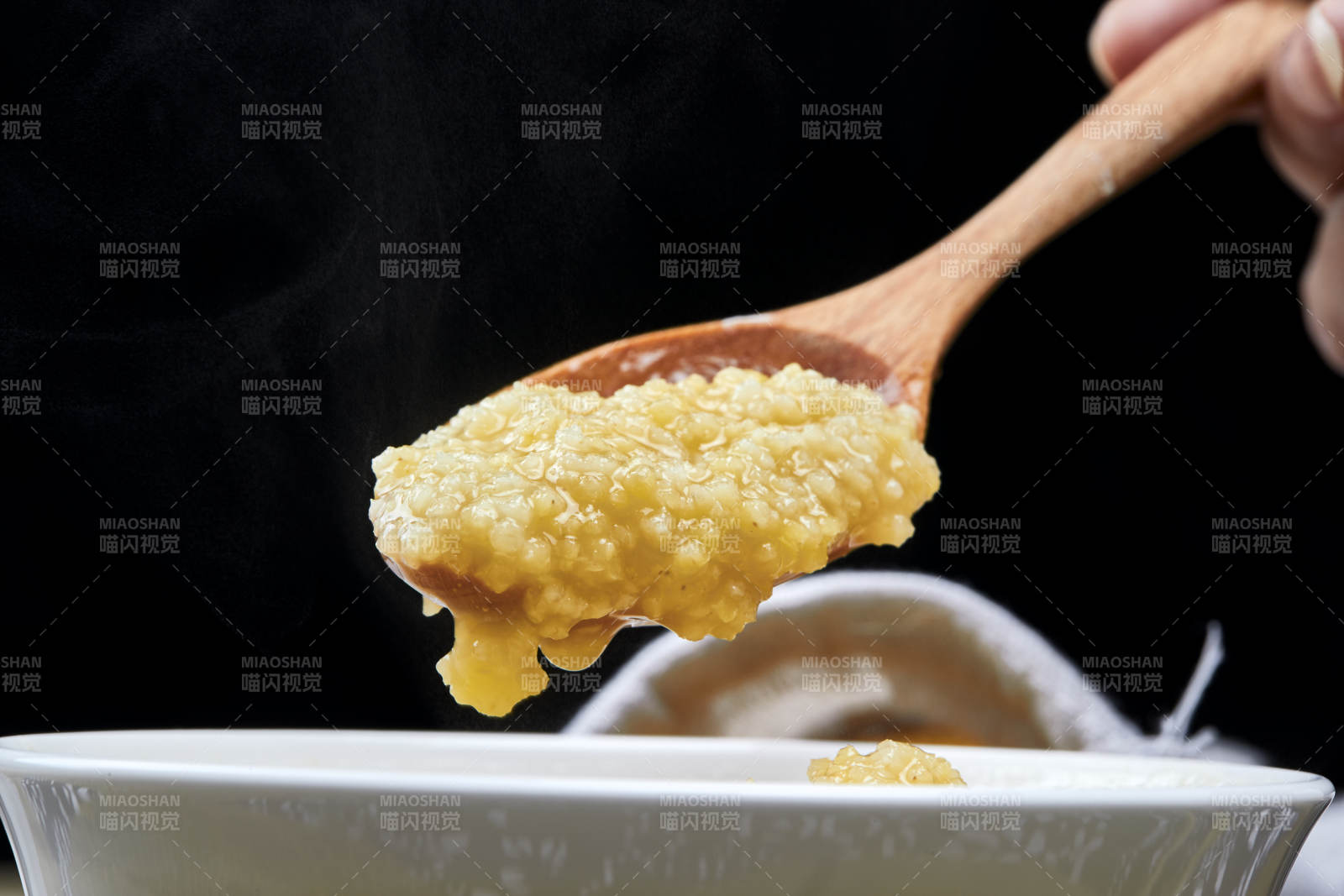 手持木勺㧟起的美味香浓小米粥