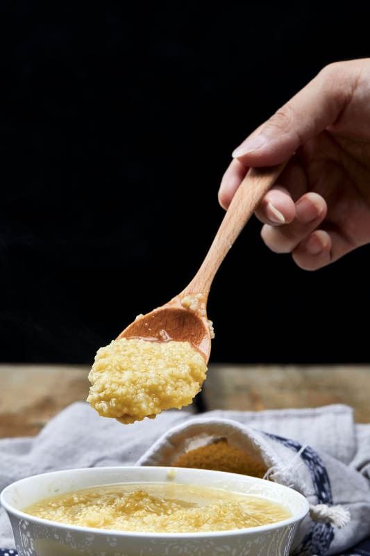 手持木勺㧟起的美味香浓小米粥