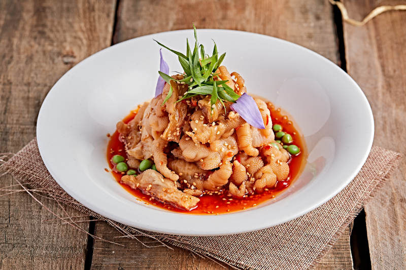 白色瓷盘装的红油酸辣脱骨凤爪