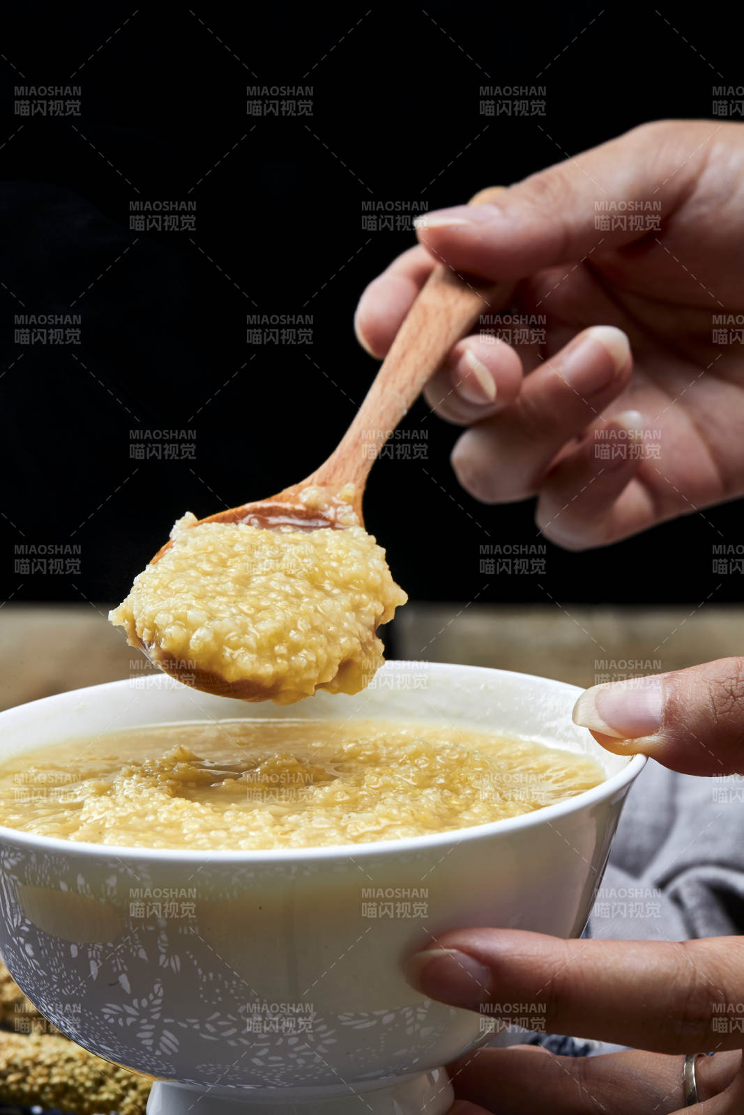 手持木勺㧟起的美味香浓小米粥