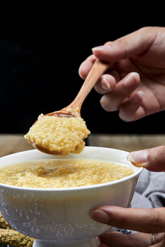 手持木勺㧟起的美味香浓小米粥