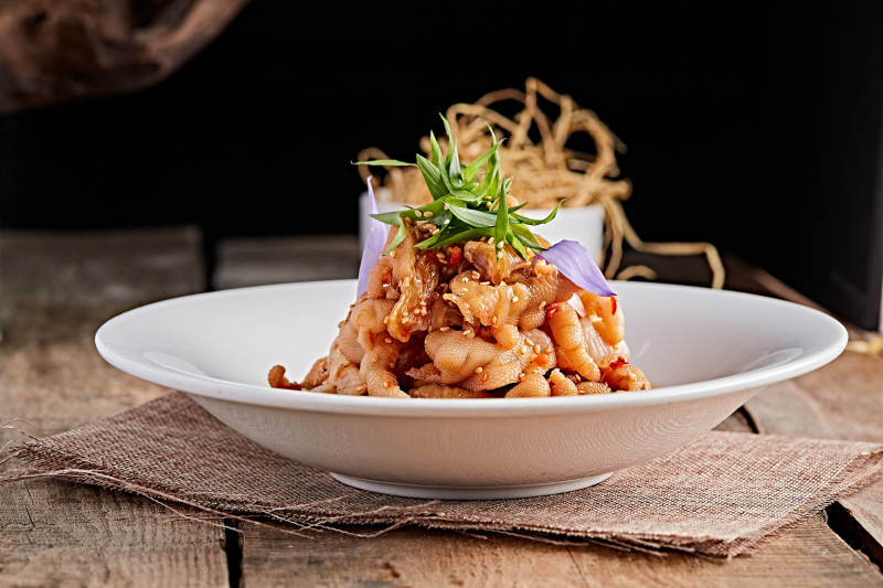 白色瓷盘装的红油酸辣脱骨凤爪