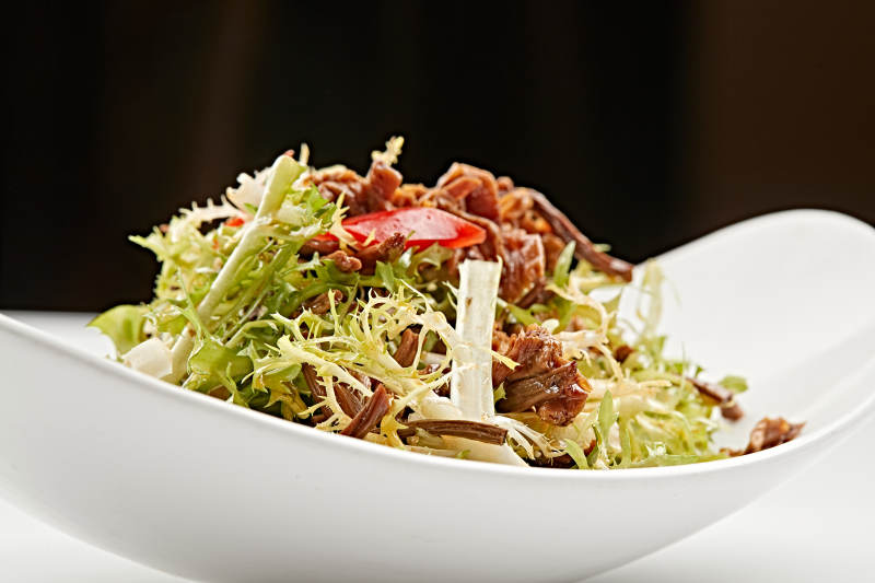 白色瓷盘装的苦菊炝拌茶树菇