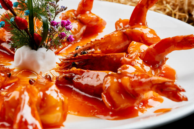 白色瓷盘装的浇汁油炸开背大明虾