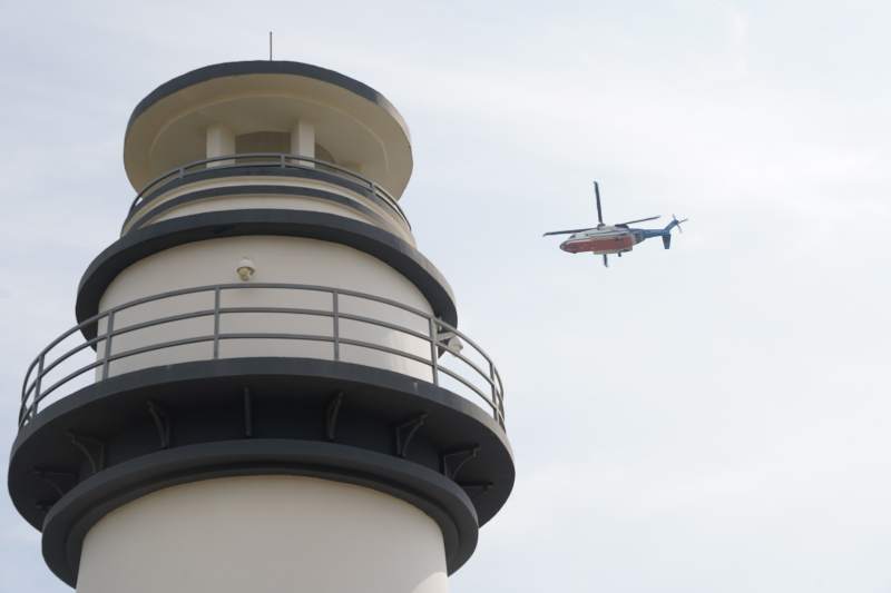 灯塔旁直升机飞过海岸