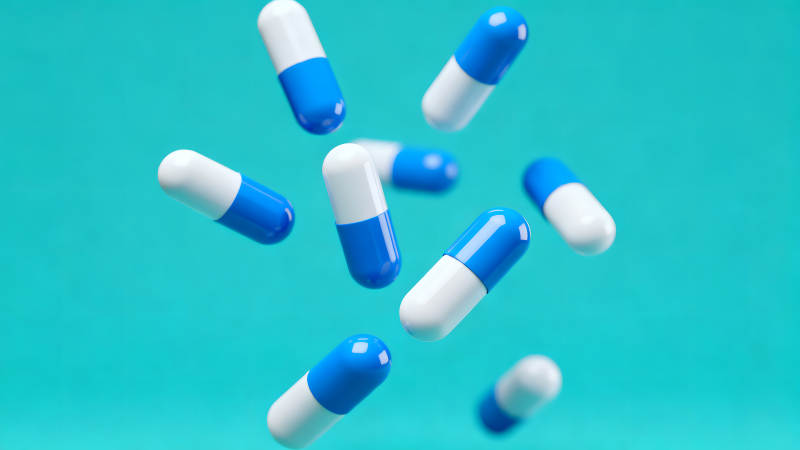 蓝色药丸悬浮在蓝色的背景上-图片