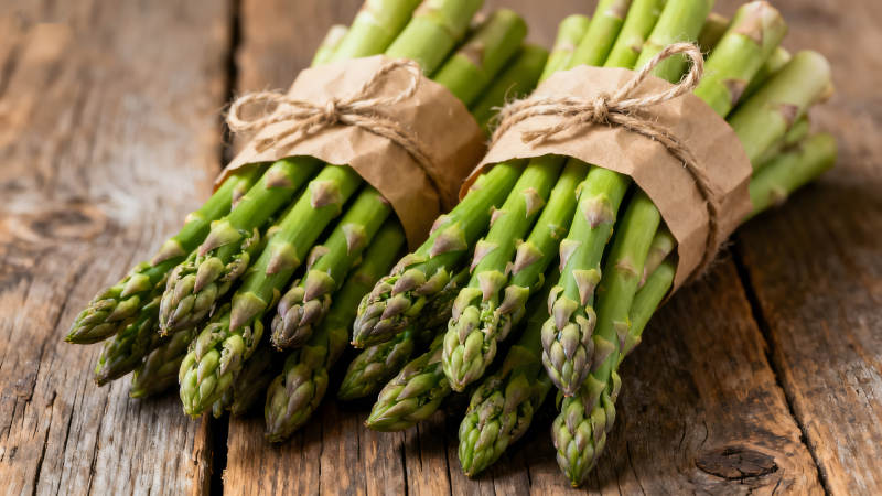 新鲜的芦笋捆绑在木质表面-图片