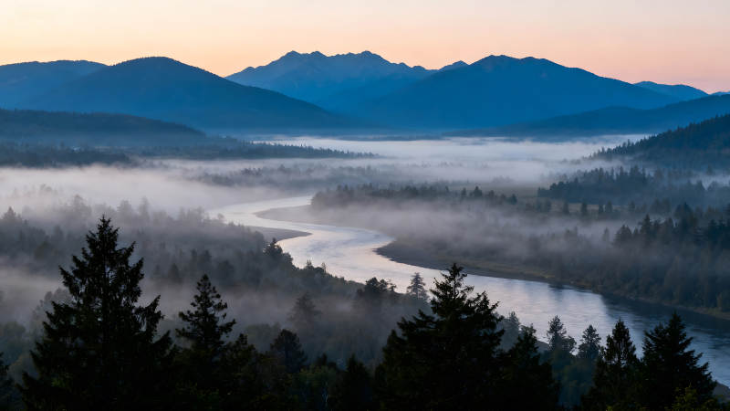 蜿蜒河流穿過山谷云霧繚繞的景象-圖片