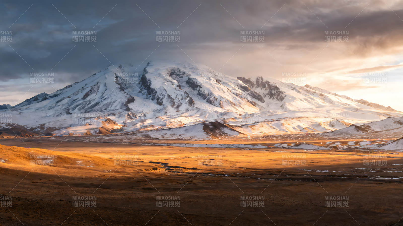 雪山下的金色平原陽光照射下的壯麗景色-圖片