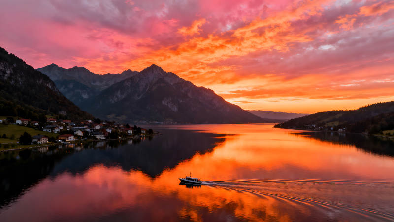 湖光山色下的絢麗晚霞與航行小船-圖片