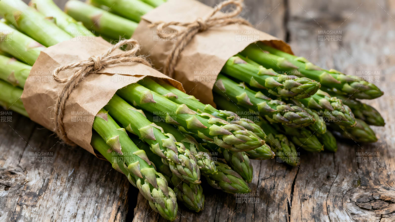 两束新鲜的芦笋用纸包裹着-图片