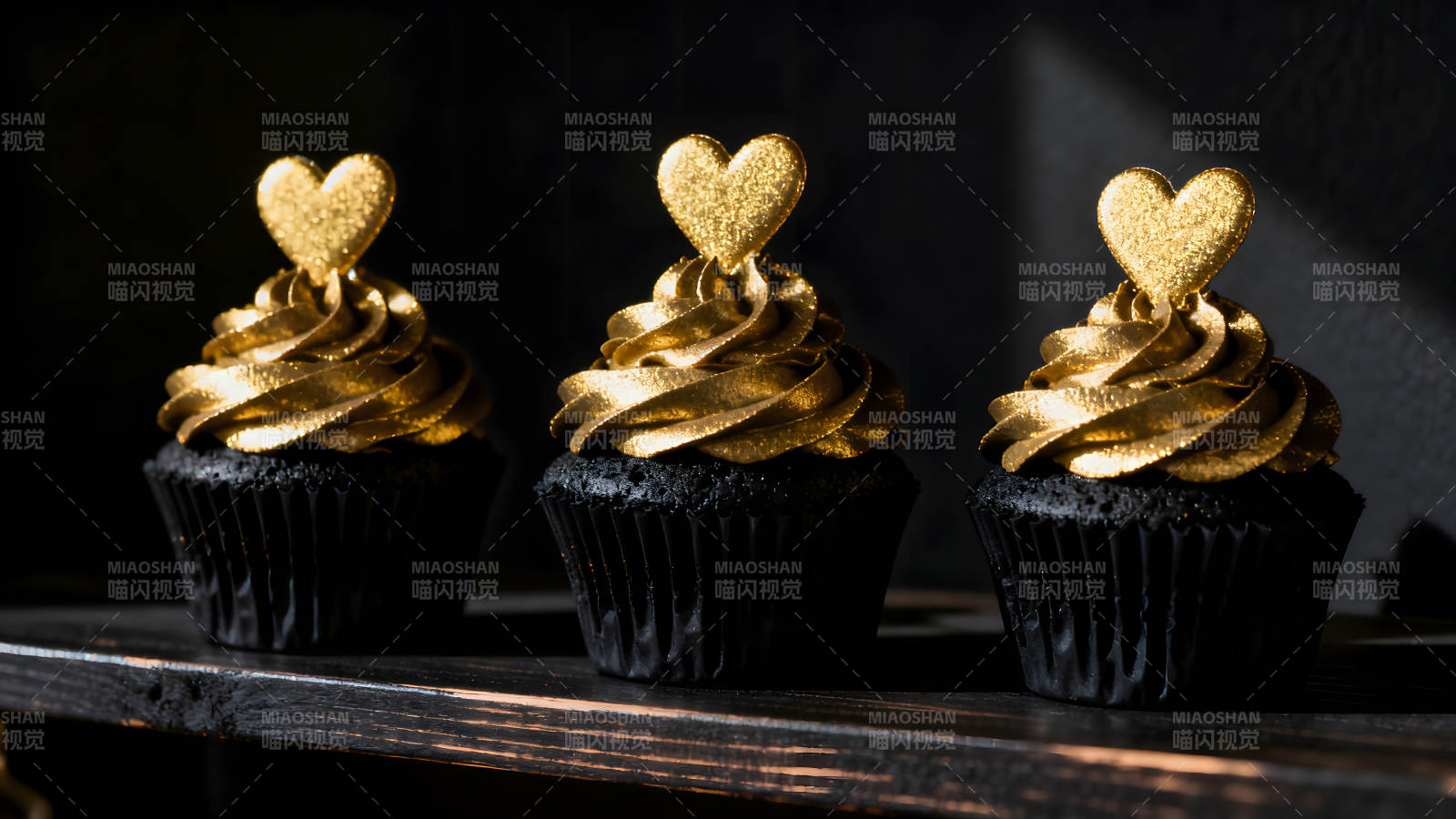 金色爱心纸杯蛋糕在黑色背景上-图片
