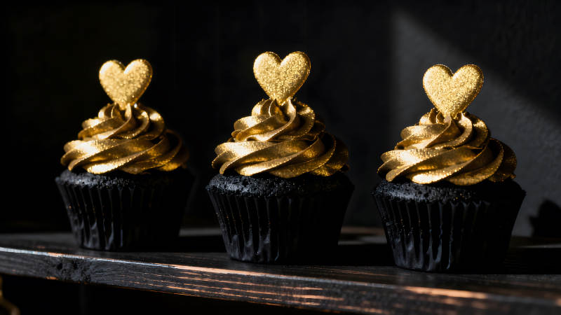 金色爱心纸杯蛋糕在黑色背景上-图片